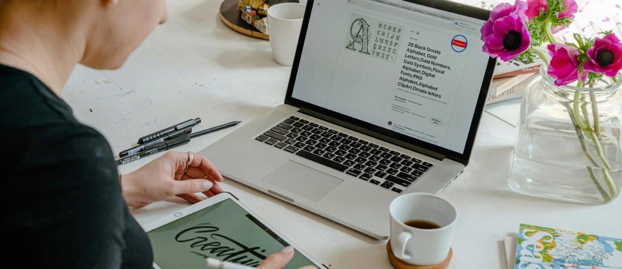 A woman works creatively with a tablet and laptop in a bright, colorful office space.